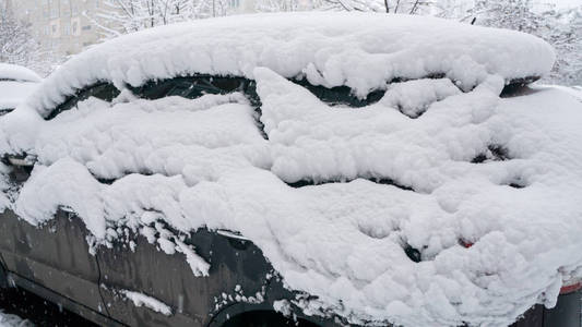 汽车上覆盖着厚厚的一层雪。 大雪的负面后果。 汽车的左边被雪覆盖