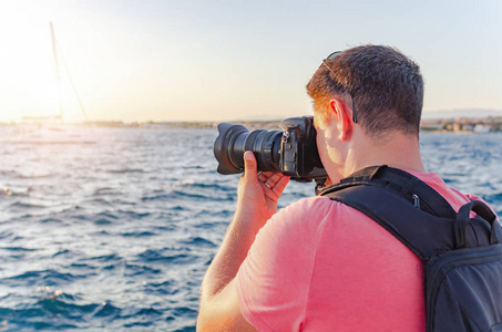男子拿着相机拍摄海岸上的日落