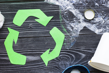 环保生态与循环利用概念回收标志与垃圾在深色木制背景上特写照片