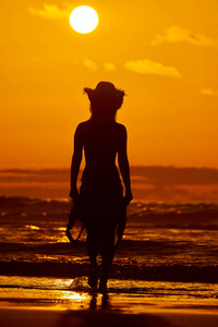 夏日夕阳下，沙滩上的年轻女子剪影