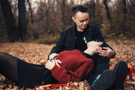 年轻的男人和年轻的女人坐在秋天的森林里的上。