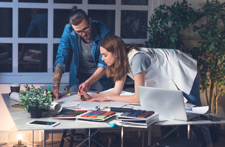 晚上高加索两个年轻的高加索设计师,一男一女,晚上一起在办公室工作.