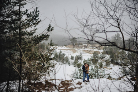 白雪皑皑的冬景中年轻幸福夫妇的肖像