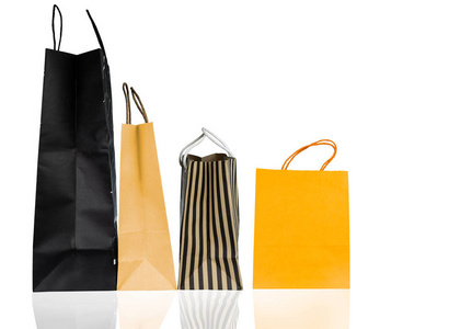 白色背景上隔离的四个纸质购物袋。购物袋有蓝色棕色和黄色。折扣销售概念。礼品袋。消费主义概念。圣诞或新年礼物包。