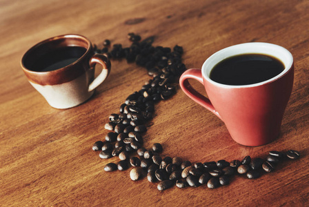 一个红色和棕色的杯子站在木桌上，咖啡豆放在曲线上