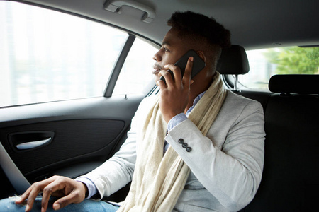 年轻商人在汽车后座用手机说话的画像