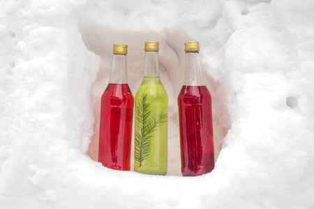 多种颜色的瓶子。雪中带酒精的瓶子