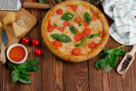 带西红柿奶酪和新鲜罗勒叶的比萨饼的顶部，放在木桌上