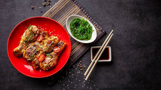 日本和中国菜的概念。 鸡肉炒腿与辣椒芝麻朱卡沙拉中国豌豆在黑桌上。 亚洲菜。 俯视图平躺