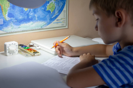 家庭教育。男孩用钢笔在传统的白色记事本纸上手写英语考试。男孩给朋友写信。放学后在家工作