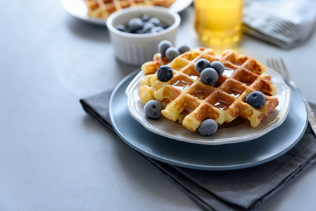 比利时华夫饼与蓝莓和蜂蜜在灰色的木制背景。 自制健康早餐。 选择性聚焦