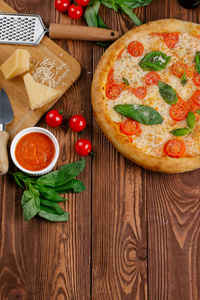 带西红柿奶酪和新鲜罗勒叶的披萨的顶部景观，放在木桌上