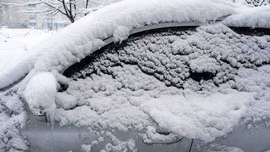 汽车上覆盖着厚厚的一层雪。 大雪的负面后果。 汽车的左边被雪覆盖