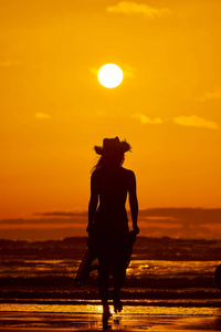 夏日夕阳下，沙滩上的年轻女子剪影