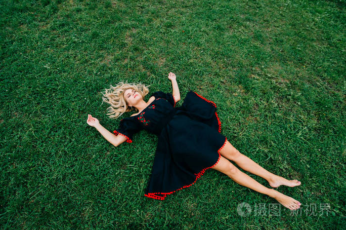俯视着穿着黑色衣服躺在绿草上的美丽女子