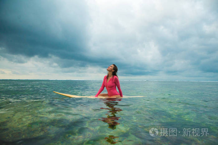 美丽的女人在冲浪板上游泳