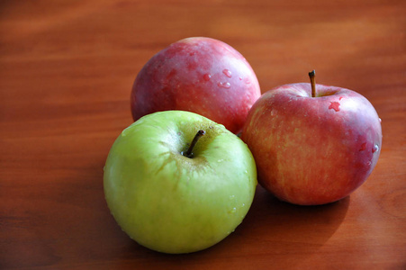 把两个红的一个绿的成熟的苹果和几滴水放在上面选择性地聚焦