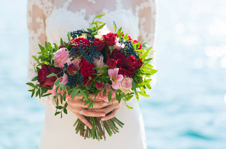 明亮的婚礼花束玫瑰和接骨木浆果举行在新娘手中