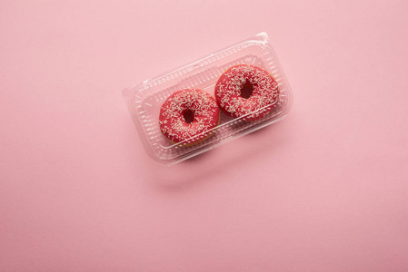粉红色背景的甜釉甜甜圈的顶部视图
