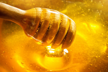 金色的蜂蜜从勺子里流下来。健康食品理念。健康饮食。饮食。选择性对焦