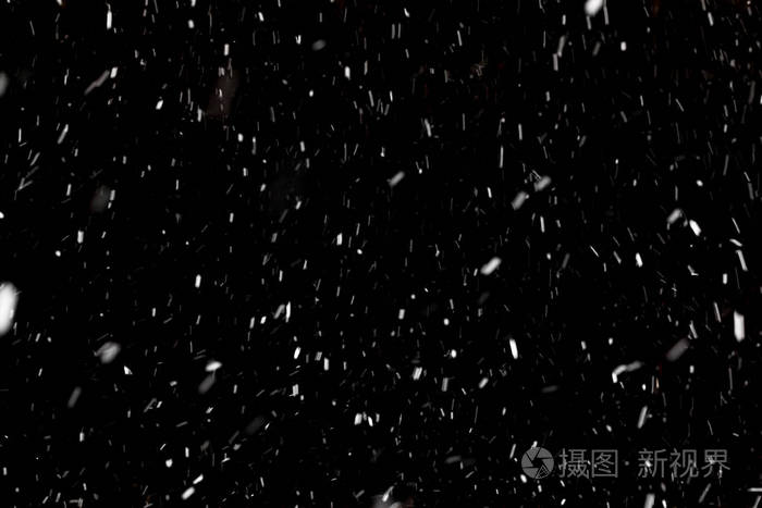 黑色背景上落下的雪. 暴风雪. 不同大小的雪花在正面平均和距离拍摄