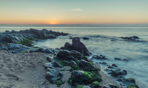 西班牙NerjaMalagaandalusi2018年12月8日黄昏日出在海滩上，一些岩石前面的图像。