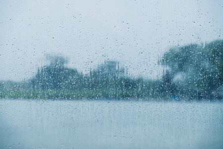 雨天概念。 玻璃窗上的雨滴。 乡村的河流和树木，如外景