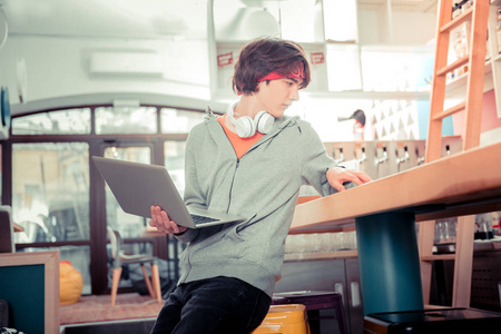 在咖啡厅使用笔记本电脑工作的青少年