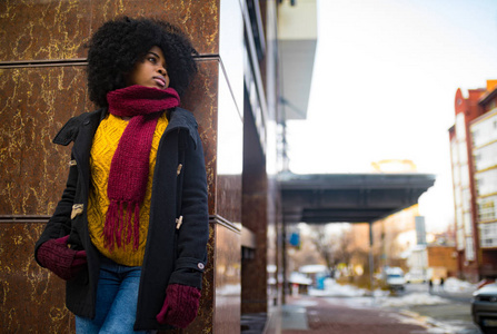 年轻的黑人妇女站在城市街道的大楼旁边。