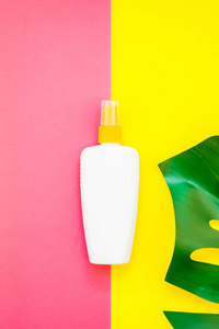 热带丛林棕榈怪物树叶和防晒霜空白瓶模型在明亮的黄色和粉红色的双酮纸背景。 暑假创意平面布局概念模板文本