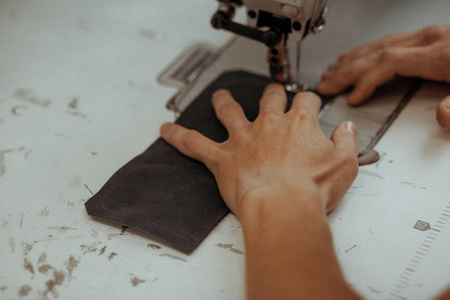 用皮革关闭缝纫机的工作部件。主人的手缝制皮革制品。手工制作的概念
