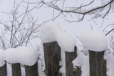 在一个冬天的阴天，覆盖着白雪的旧木栅栏。