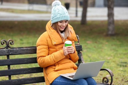 在公园里用笔记本电脑喝咖啡的美女