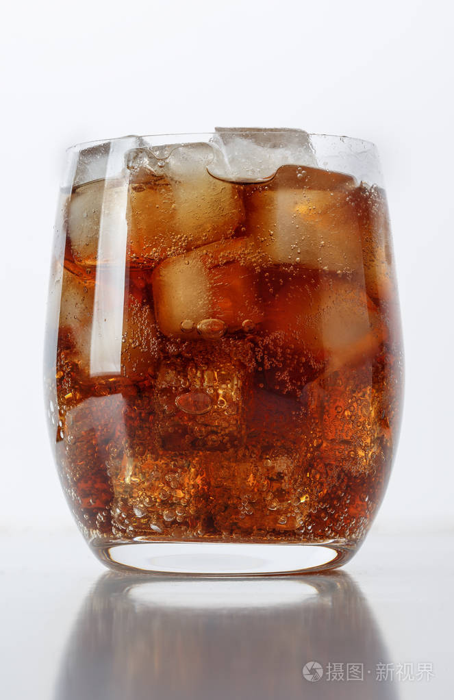 一杯加冰的可口可乐放在白色的桌子上喷在周围