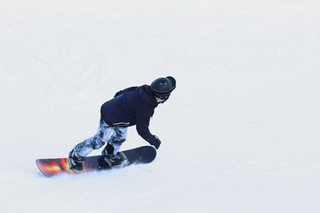 滑雪者骑在滑雪场的雪板上沿着雪覆盖的斜坡行驶。 冬季运动。 自由式和回转下降。 极端寒冷的设备。 在寒冷中促进健康的活动。 青年