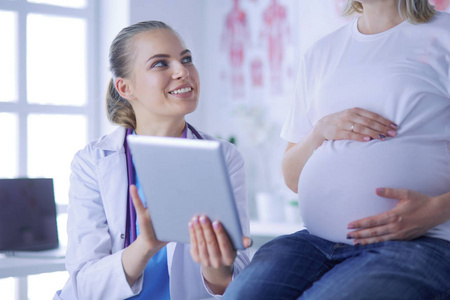 微笑的妇女医生显示图片在片剂对怀孕的妇女在医院