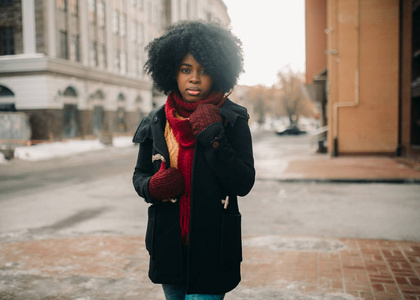 年轻的黑人妇女站在城市街道上，背景是建筑物。