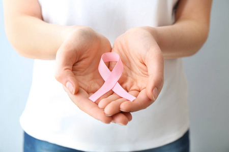 在浅色背景特写上有粉红色丝带的女人。 乳腺癌意识概念