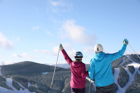 幸福的一对夫妇，带着滑雪设备，坐在雪山上，有文字空间。 寒假