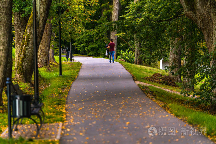 年轻人在公园里的路上,手里拿着花,在树林间空地上,写着阳光明媚的