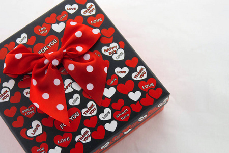 情人节 一个黑色的礼品盒，里面有红色和白色的心，上面写着孤立在白色背景上的爱信息。 上面的风景。