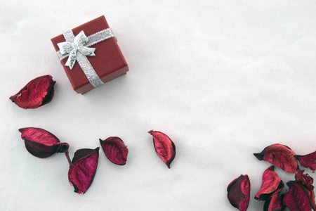 情人节 红色盒子的礼物与银丝带和干燥的红色花瓣和装饰银条纹隔离在白色背景。 上面的风景。
