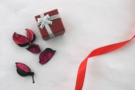 情人节 红色盒子的礼物与银丝带和干燥的红色花瓣和装饰红色条纹隔离在白色背景。 上面的风景。
