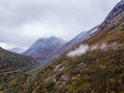 无人驾驶飞机照片的森林在挪威的山区与云层覆盖的山的概念，旅行和平与和谐