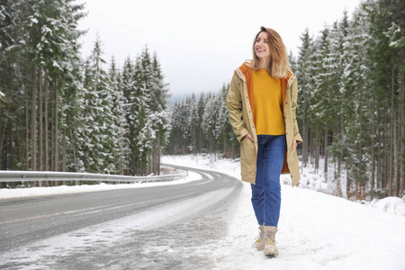 年轻女子走在雪林附近。 寒假