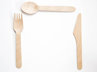 一种可持续和可回收的木制餐具，包括一把刀叉和的餐刀叉和勺子，以及带有复制空间的白色背景。