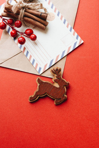 手工制作的木鹿在红色背景信封和贺卡肉桂棒。 圣诞祝福