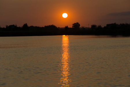 橙色的太阳落在湖面上，光线在水中反射