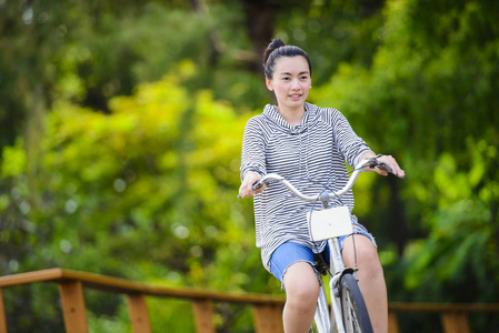 年轻的亚洲女人在公园里骑老式自行车