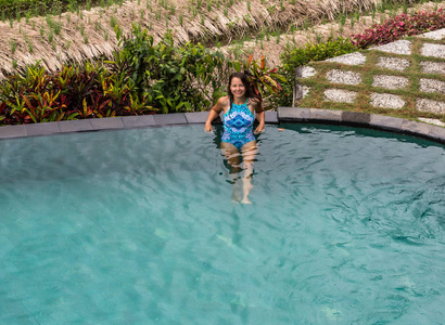 的女人，享受着阳光在夏天豪华度假村的游泳池